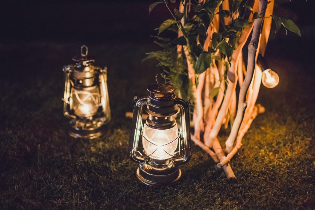 Night wedding ceremony, wooden arch on party decorated with old vintage lantern with candle